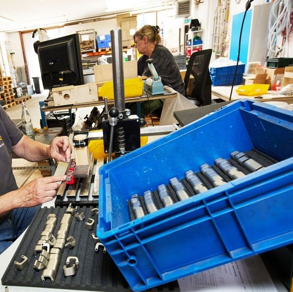 Eine blaue Plastikbox mit Produkten und einer Mitarbeiterin im Hintergrund